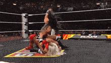two women are wrestling in a ring with a sign that says raw on it