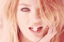 a close up of a woman 's face with a pink heart in her mouth .