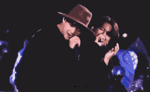 a man in a cowboy hat is hugging another man in a black jacket
