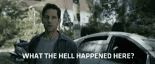 a man is standing in front of a car and asking what the hell happened here