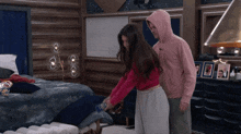 a man in a pink hoodie stands next to a woman in a red sweater
