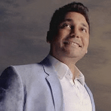 a man wearing a blue jacket and white shirt is smiling and looking up .