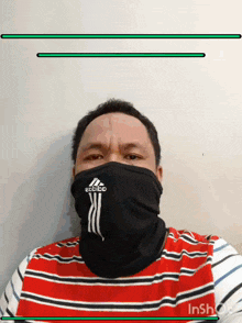 a man wearing a red and white striped shirt and an adidas face mask