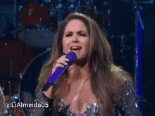a woman is singing into a purple microphone with the hashtag lialmeida05