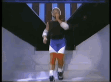 a man in a wrestling outfit is walking down a set of stairs and covering his mouth with his hand .