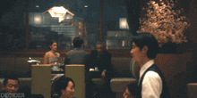 a man in a vest is talking to a woman in a diner and the words decider are on the bottom right