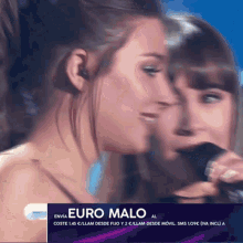 a woman singing into a microphone with a euro malo ad behind her