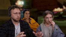 a man and two women wearing headphones are sitting in a room