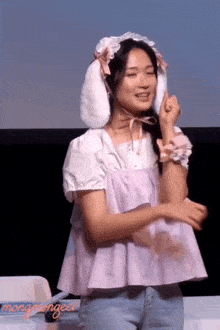 a woman wearing bunny ears and a purple top is smiling and dancing