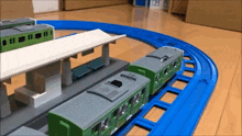 a green toy train is going down a track