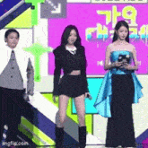 three women are standing on a stage in front of a sign that says ' imgflip.com ' on it