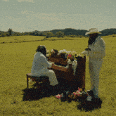 a man in a cowboy hat is standing next to a man playing a piano
