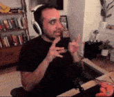 a man wearing headphones is sitting in front of a microphone in a room .