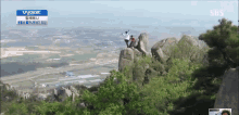a person standing on top of a rock with a sbs logo in the corner