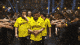 a man wearing a yellow shirt that says vitality stands in front of a crowd