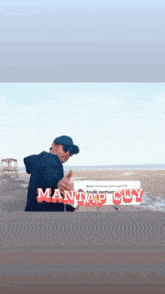 a man standing on a beach with mantap cuy written in red