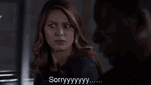 a woman in a superhero costume is talking to a man in a dark room and saying sorry .