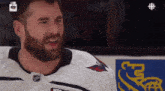 a man with a beard is wearing a white jersey with a fox logo on the front