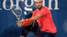 a man in a red shirt is holding a tennis racquet in front of the word organ