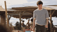 a man in a striped shirt is walking in front of a restaurant