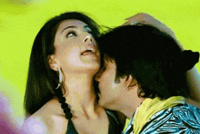 a man is kissing a woman on the neck while a woman looks on .