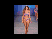 a model in a bikini walks down the runway at a fashion show