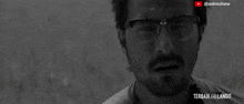 a black and white photo of a man wearing glasses and a beard