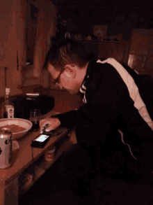 a man is looking at a cell phone next to a can of coca-cola