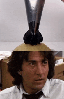 a man in a white shirt and tie is looking at a black object that says w on it