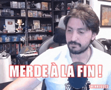 a man sitting in front of a microphone with the words merde a la fin written on it