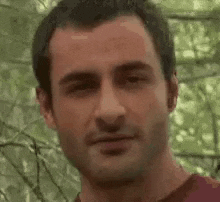 a close up of a man 's face with a blurred background of trees .