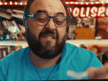 a man with glasses and a beard is smiling in front of a sign that says ' polisa '