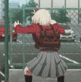 a girl with a backpack is standing in front of a fence