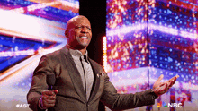 a man in a suit singing into a microphone with nbc written on the bottom