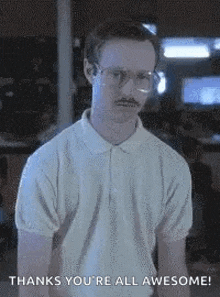 a man with glasses and a mustache is standing in front of a sign that says `` thanks you 're all awesome ! ''