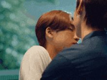 a man kissing a woman on the forehead with trees in the background