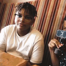 a young boy wearing glasses is sitting at a table with a table number .