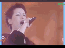 a woman is singing into a microphone on a tv screen