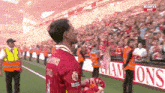 a man wearing a red jersey with the word champions on it stands on a soccer field