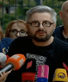 a man with glasses and a beard is speaking into a microphone that says bbc