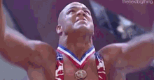 a man is wearing a medal around his neck and his arms are raised in the air .