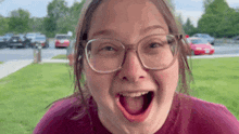 a young girl wearing glasses and a purple shirt is making a funny face .