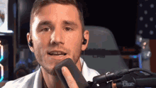a man wearing earbuds and a blue microphone
