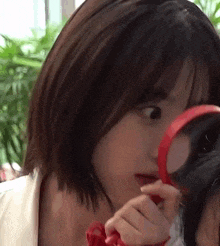 a woman is looking through a magnifying glass at herself .
