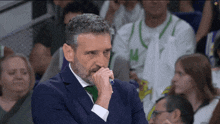 a man in a suit holds his hand to his mouth