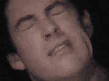 a close up of a man making a face with his eyes closed .