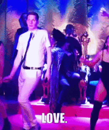 a man in a white shirt and tie is dancing with a woman in a black dress and the word love is visible in the background