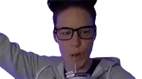 a woman wearing glasses is drinking through a straw from a glass .