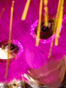 a close up of a purple feathered object with yellow sticks
