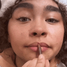 a close up of a woman applying lip pencil